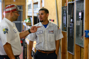 Two JDV Electric technicians servicing a circuit panel.